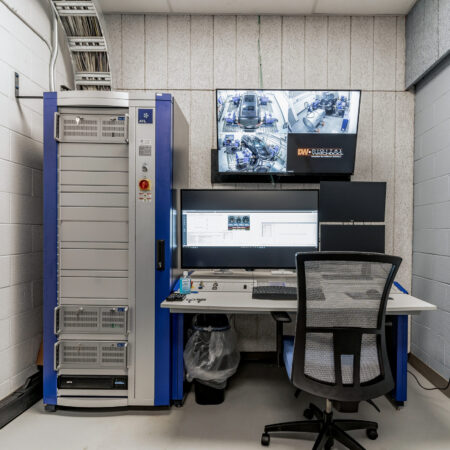 Control panel setup for operating the thermal chamber in MARC 118, featuring a large equipment rack on the left and a desk with multiple monitors displaying control software and security camera feeds.