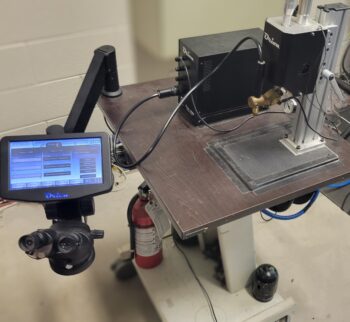 Sunstone Orion arc-welder with a touch screen displaying various setup options. The welder is placed on a table, and a fire extinguisher is located underneath the screen for safety.